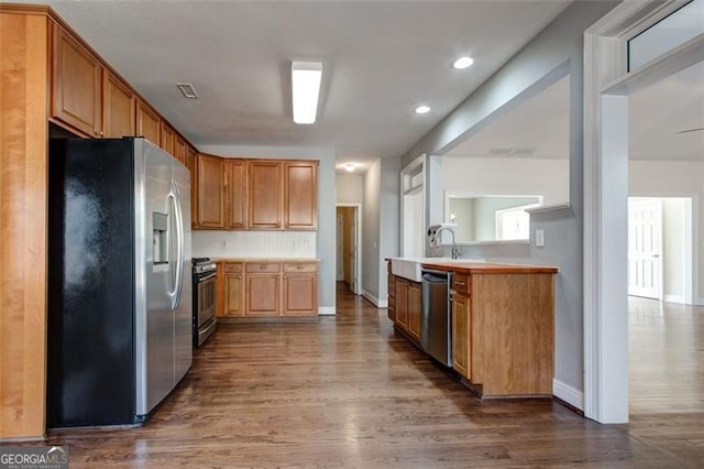 kitchen featuring appliances with stainless steel finishes, decorative backsplash, dark hardwood / wood-style floors, and sink