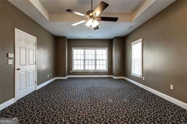 carpeted spare room with ceiling fan and a tray ceiling