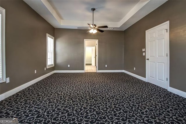 unfurnished room with ceiling fan, carpet floors, and a tray ceiling