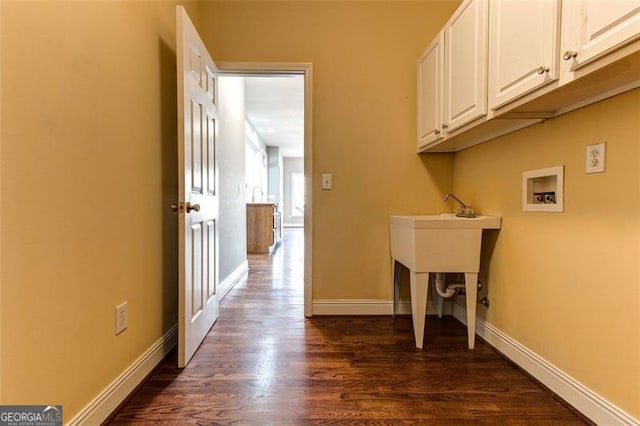 clothes washing area with washer hookup, dark wood-type flooring, and cabinets