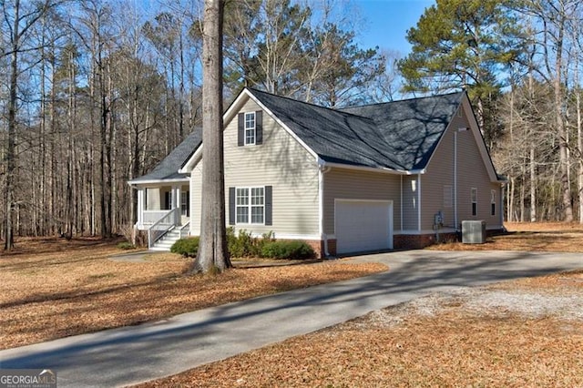 view of home's exterior featuring central AC unit, covered porch, and a garage