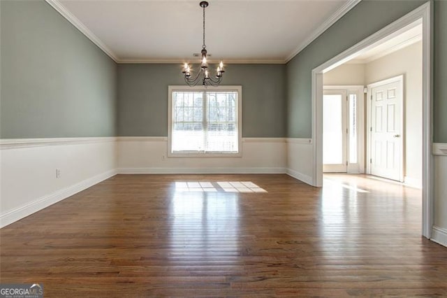 spare room featuring a notable chandelier, dark hardwood / wood-style flooring, and crown molding