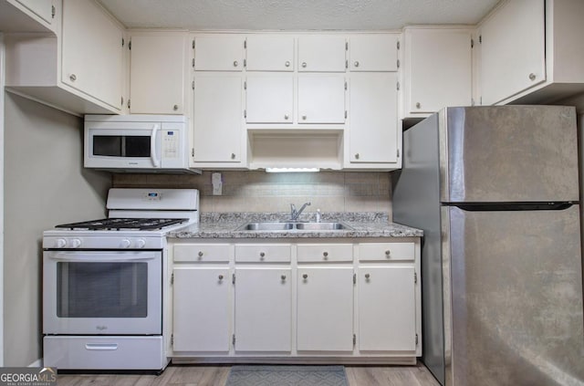 kitchen with sink, white cabinets, tasteful backsplash, and white appliances