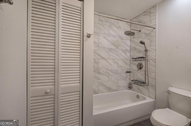 bathroom featuring a textured ceiling, toilet, tiled shower / bath combo, and tile patterned flooring