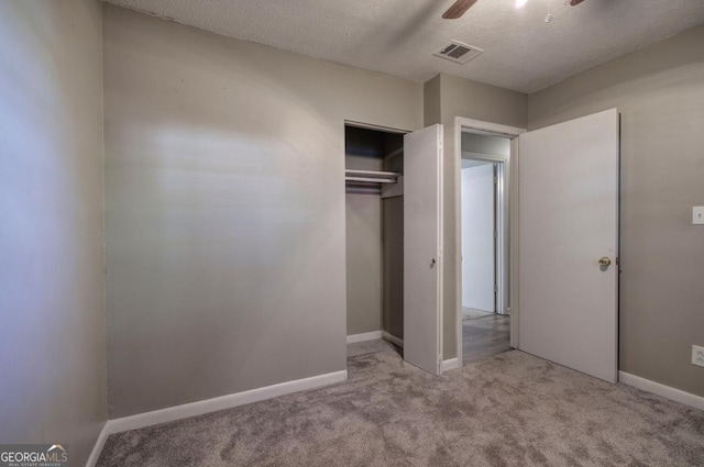 unfurnished bedroom featuring a textured ceiling, ceiling fan, a closet, and light colored carpet