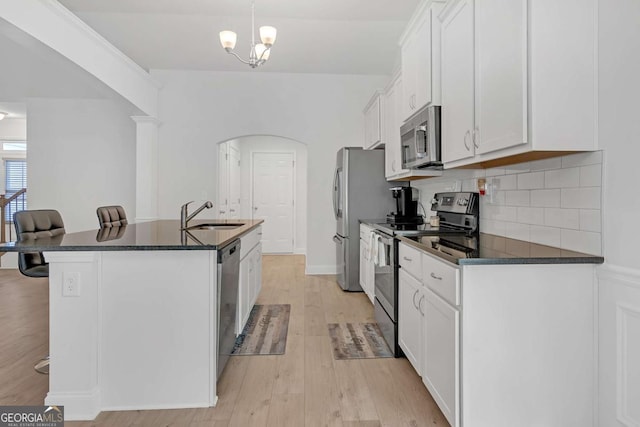 kitchen with white cabinetry, stainless steel appliances, backsplash, a kitchen breakfast bar, and sink