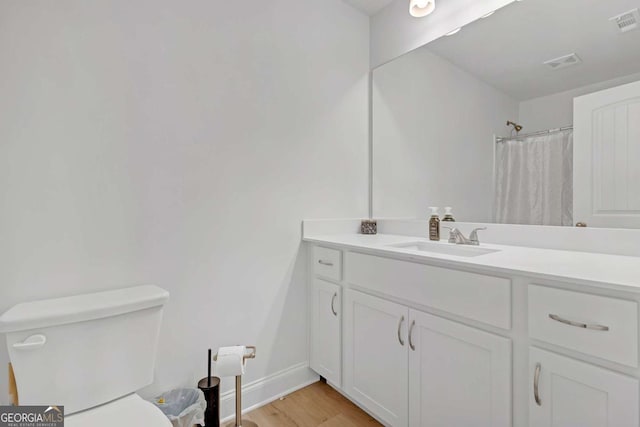 bathroom with toilet, vanity, walk in shower, and hardwood / wood-style floors