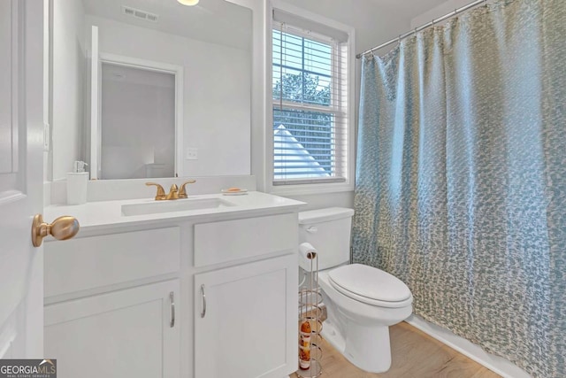 bathroom with toilet, a healthy amount of sunlight, hardwood / wood-style flooring, and vanity