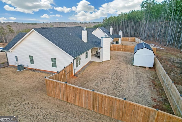 back of house featuring central AC unit and a storage unit