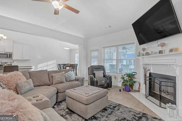 living room with ceiling fan, light hardwood / wood-style flooring, and a premium fireplace