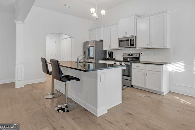 kitchen with tasteful backsplash, a center island with sink, sink, white cabinetry, and appliances with stainless steel finishes