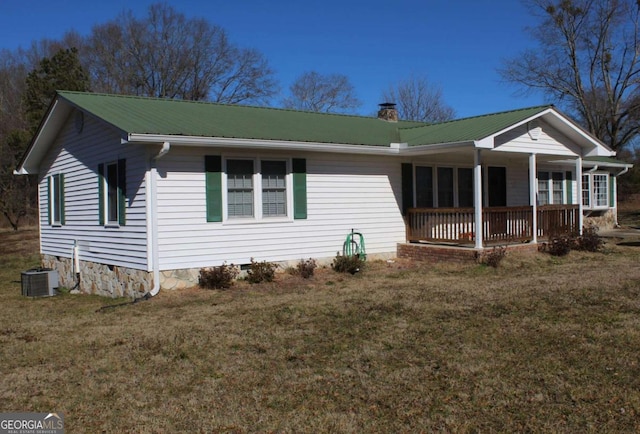 view of front of property featuring a front lawn, covered porch, and central AC