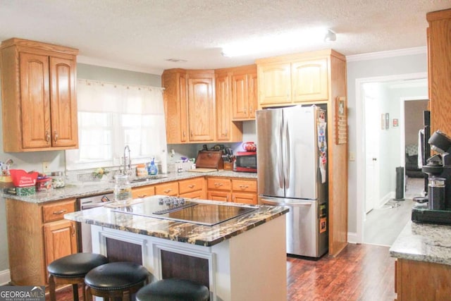 kitchen featuring a kitchen bar, stainless steel appliances, a textured ceiling, a kitchen island, and sink