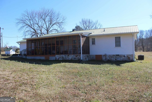 rear view of property featuring central AC unit, a yard, and a sunroom