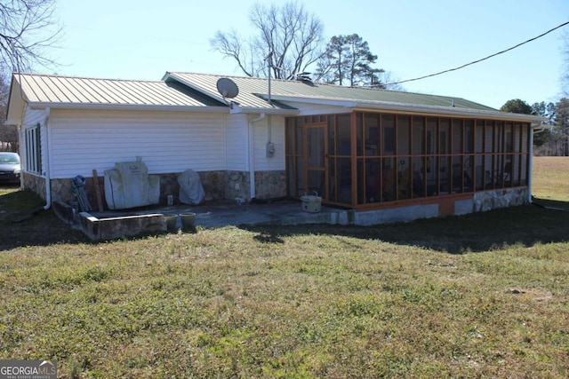 rear view of house featuring a sunroom and a yard