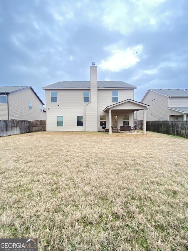 back of property with a patio area and a lawn