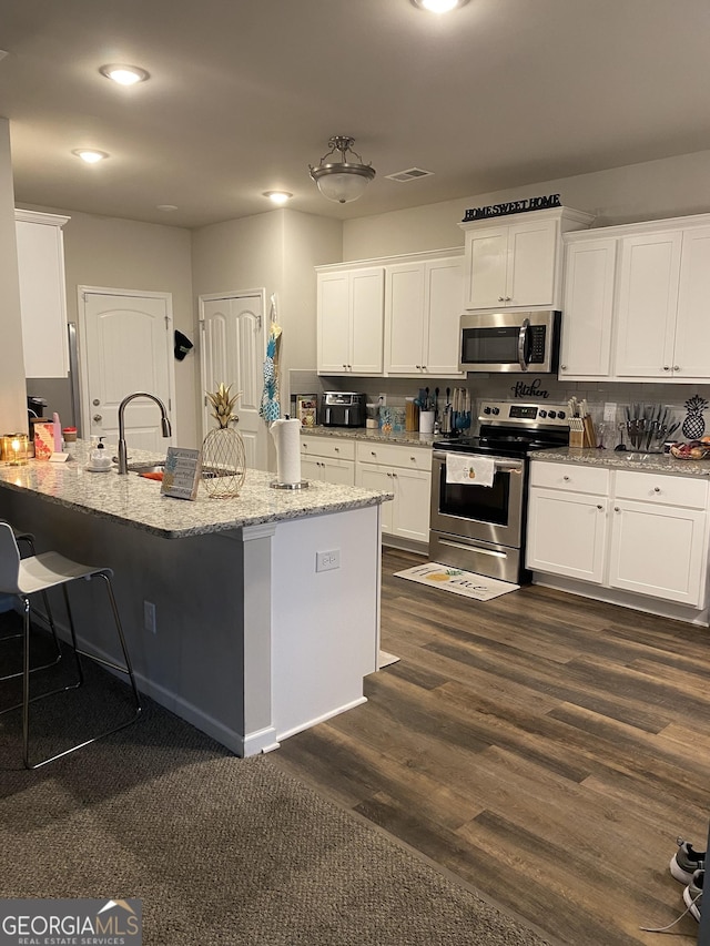 kitchen with dark hardwood / wood-style floors, sink, white cabinets, light stone counters, and stainless steel appliances