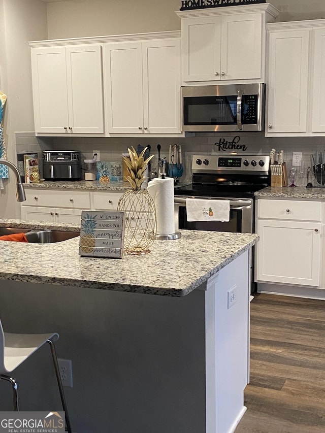 kitchen with white cabinetry, sink, light stone counters, stainless steel appliances, and dark wood-type flooring