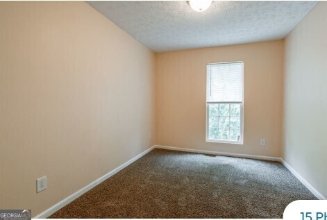 carpeted empty room featuring a textured ceiling