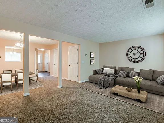 carpeted living room with an inviting chandelier and a textured ceiling