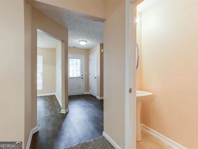 hall featuring dark wood-type flooring and a textured ceiling