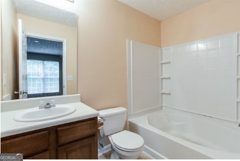 full bathroom featuring a textured ceiling, toilet, vanity, and bathing tub / shower combination