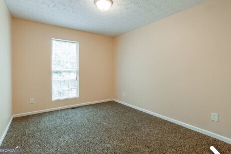 carpeted empty room featuring a textured ceiling