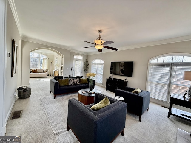 carpeted living room with ceiling fan and crown molding