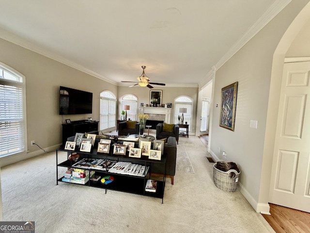 living room featuring ceiling fan, light colored carpet, and crown molding