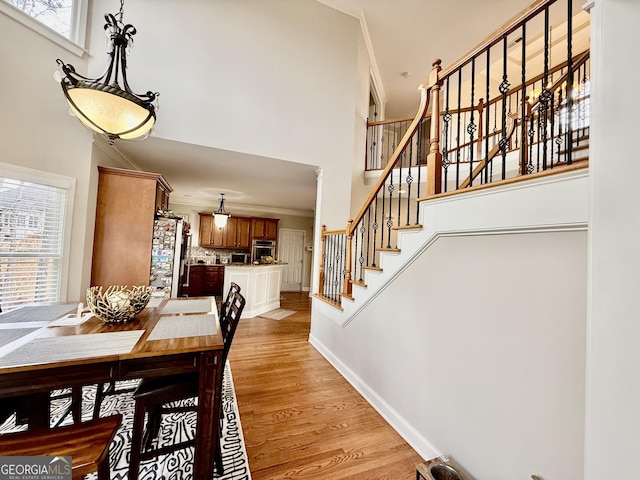 dining area with a wealth of natural light, crown molding, and light hardwood / wood-style floors