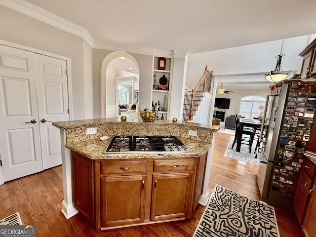 kitchen with light stone countertops, appliances with stainless steel finishes, a center island, and light hardwood / wood-style flooring