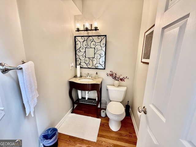 bathroom featuring toilet, wood-type flooring, and sink