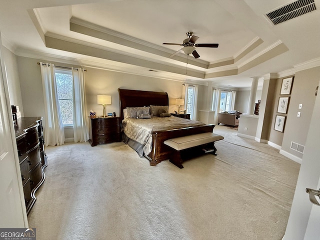 carpeted bedroom with a raised ceiling, ceiling fan, ornamental molding, and ornate columns