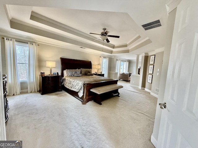 bedroom with ceiling fan, light colored carpet, a raised ceiling, ornamental molding, and decorative columns