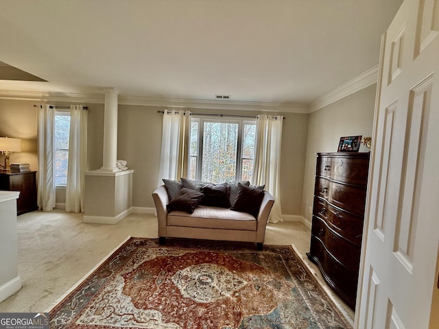 sitting room featuring light colored carpet, crown molding, and ornate columns