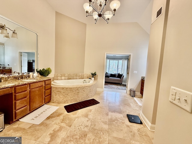 bathroom featuring high vaulted ceiling, tiled tub, vanity, and a notable chandelier