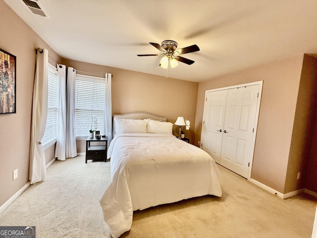 bedroom with ceiling fan, light colored carpet, and a closet