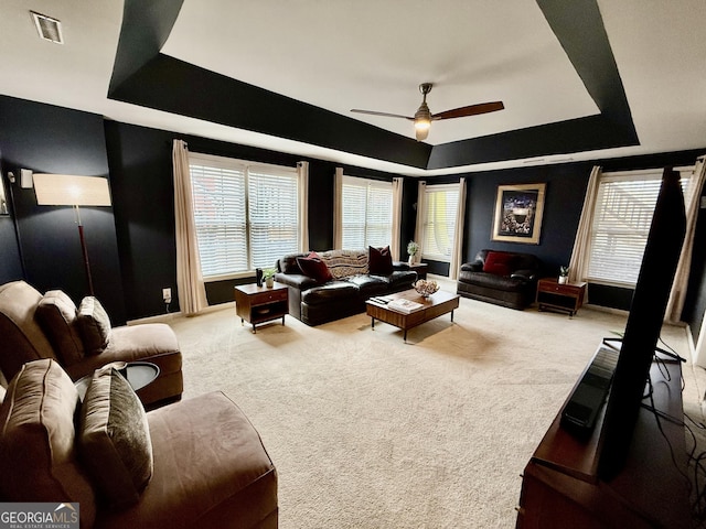 living room with ceiling fan, a healthy amount of sunlight, carpet floors, and a tray ceiling