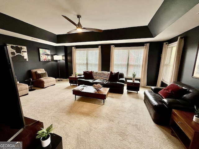 living room featuring ceiling fan, carpet, and a tray ceiling