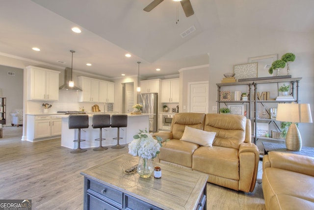 living room with ceiling fan, vaulted ceiling, and light hardwood / wood-style flooring