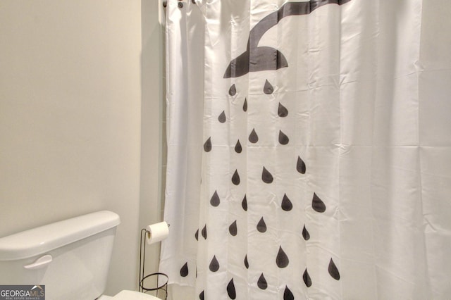 bathroom with toilet and a shower with shower curtain