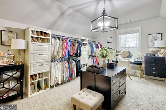 walk in closet with light carpet, vaulted ceiling, and a notable chandelier