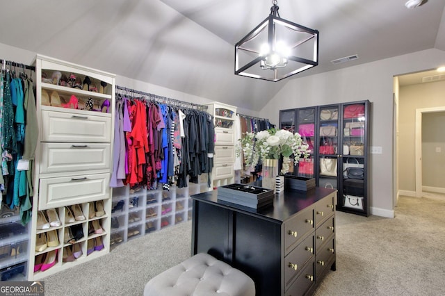 walk in closet with lofted ceiling, light colored carpet, and an inviting chandelier