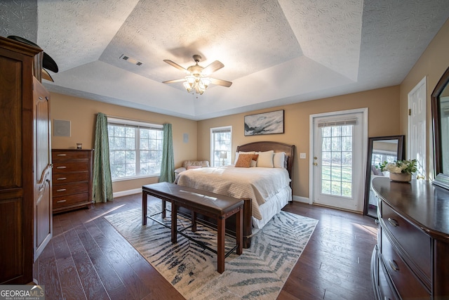 bedroom featuring ceiling fan, dark wood-type flooring, and a raised ceiling