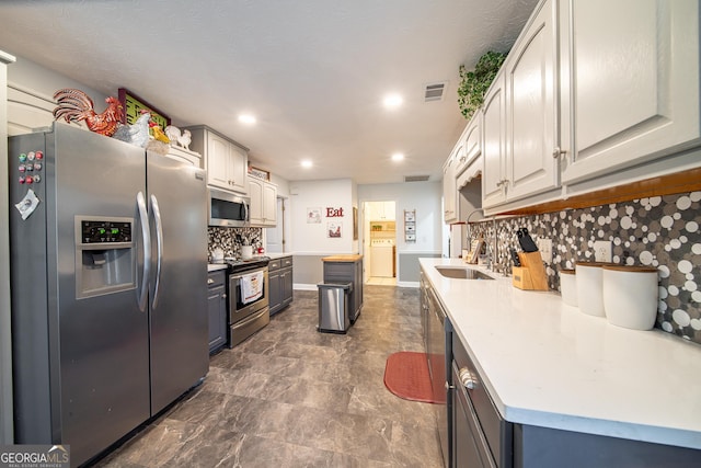 kitchen with decorative backsplash, sink, gray cabinetry, and stainless steel appliances