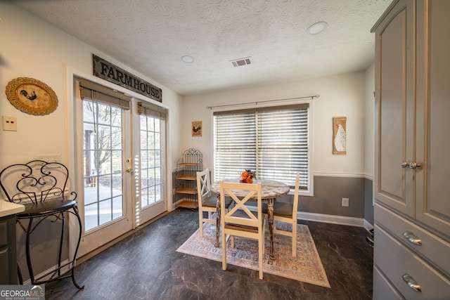 dining space with a textured ceiling and french doors