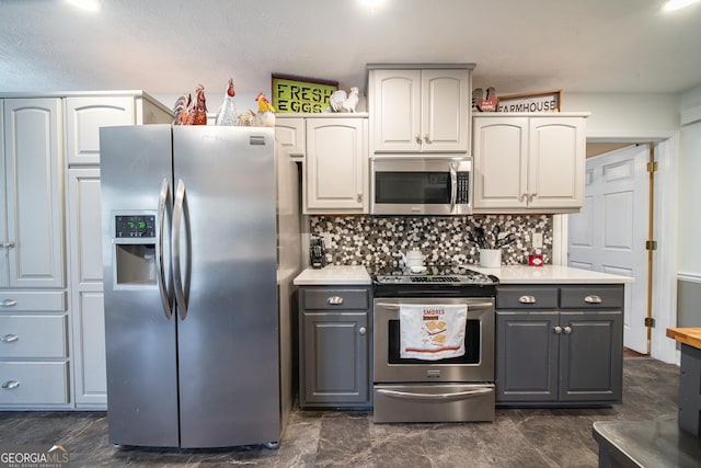 kitchen with stainless steel appliances, gray cabinetry, decorative backsplash, and white cabinets