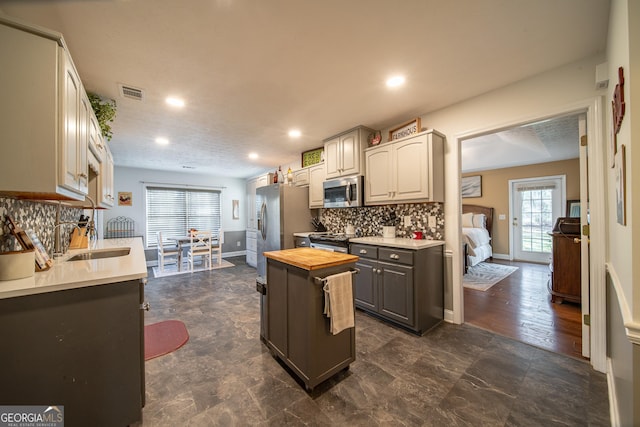 kitchen with sink, appliances with stainless steel finishes, wooden counters, and tasteful backsplash