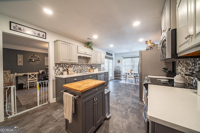 kitchen featuring wooden counters, stainless steel appliances, tasteful backsplash, sink, and gray cabinetry