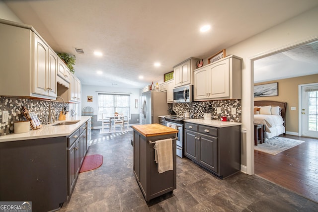 kitchen with stainless steel appliances, butcher block counters, backsplash, and sink